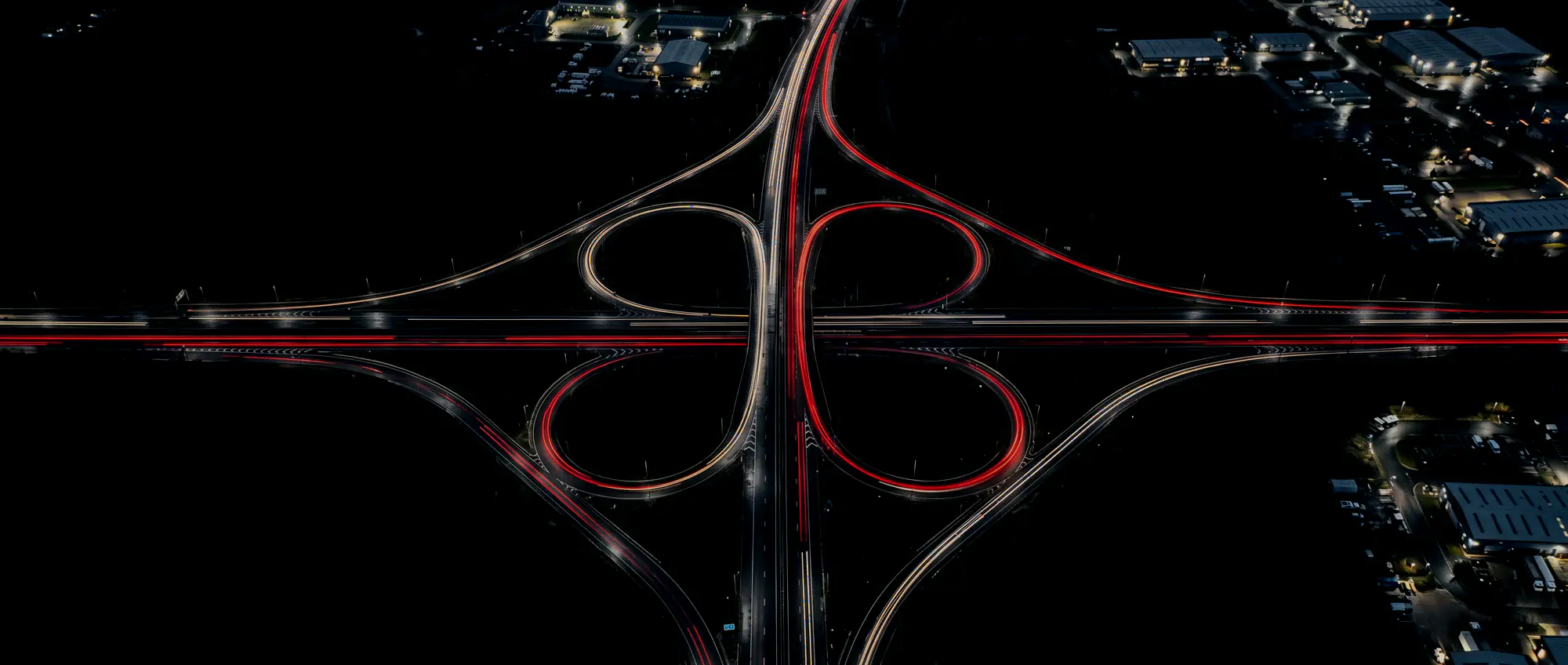 Autobahnkreuz aus der Luft bei Nacht, der Verkehr zeichnet rote Lichtbänder in die Kurven